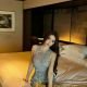 Attractive Chinese woman in a stylish top, posing on a bed in a Bangsar hotel room.